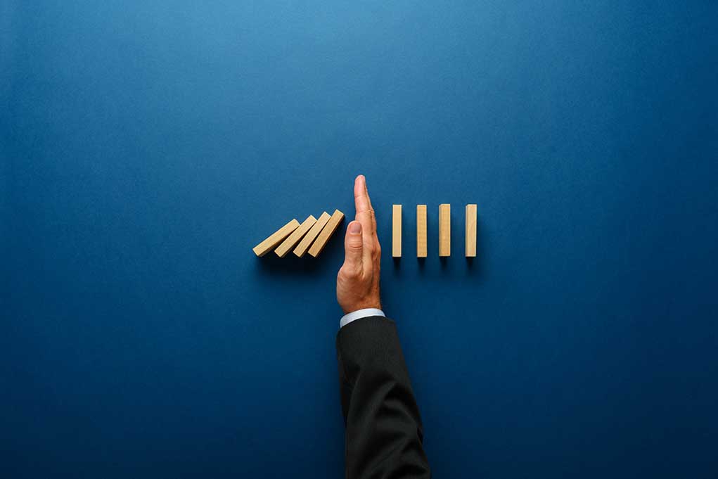 Top,View,Of,Businessman,Hand,Stopping,Falling,Dominos,In,A