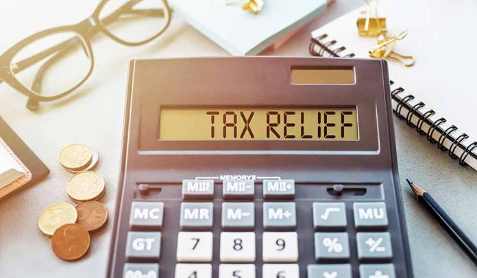1908079453 featured image Calculator display reads "TAX RELIEF" amidst coins and glasses.