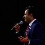 Man in suit speaking into microphone on stage