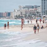 People walking and relaxing on a crowded beach.