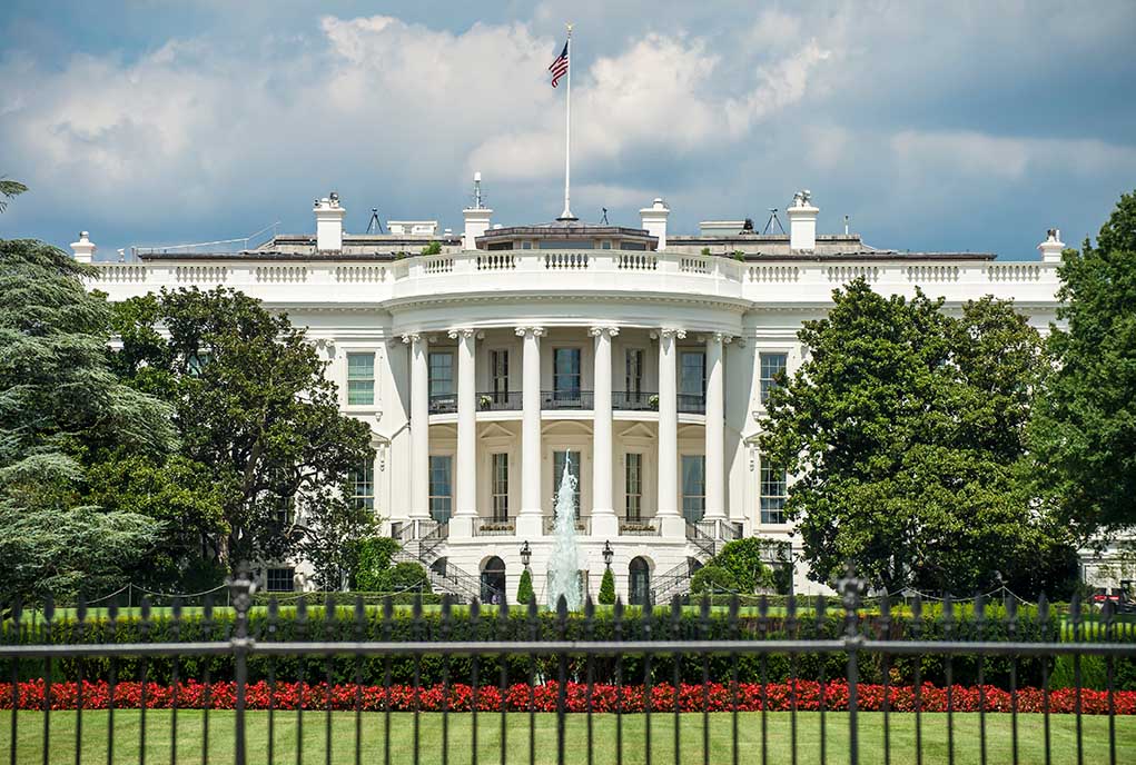1198847647 featured image White building with columns behind a black fence.