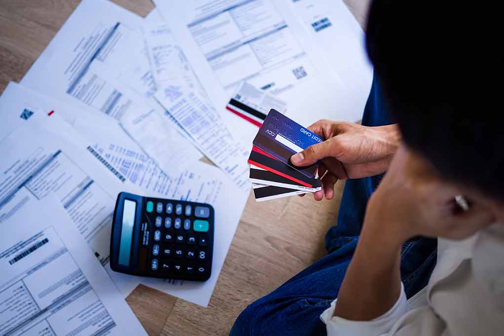 1748127269 featured image Person holding credit cards amidst bills and calculator