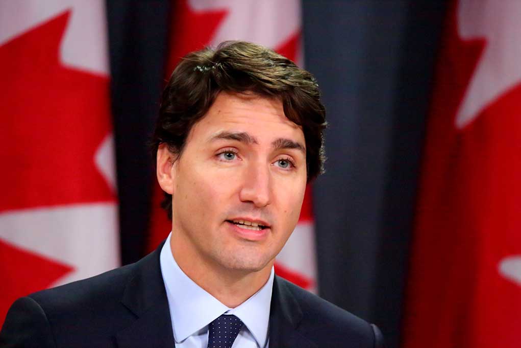 373957918 featured image Man speaking in front of Canadian flags.