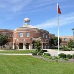 School building with flags and clear sky