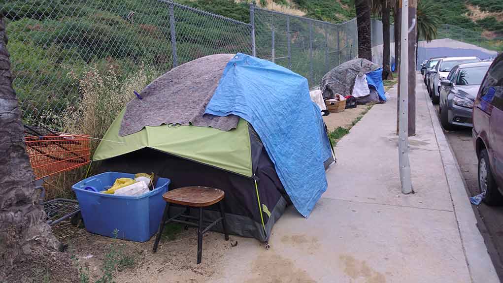 1392494762 featured image Tents and belongings set up along sidewalk.