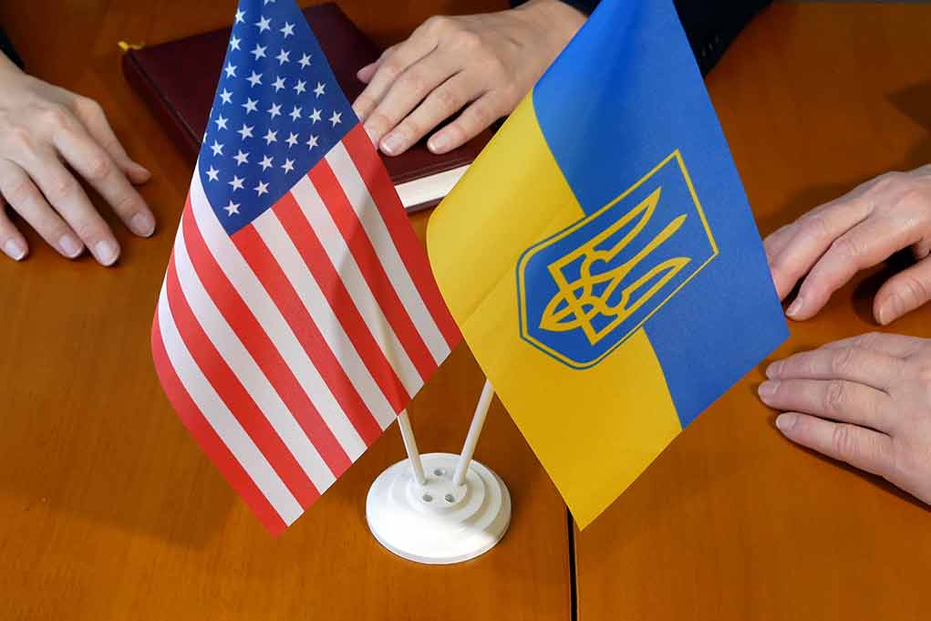2034604337 featured image US and Ukraine flags on wooden table meeting