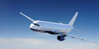 Airplane flying above clouds in blue sky