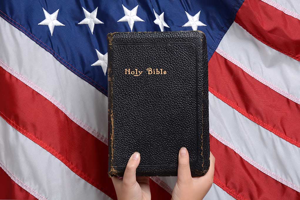 492471811 featured image Bible held in front of American flag.