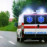 Ambulance driving on a paved road with lights flashing