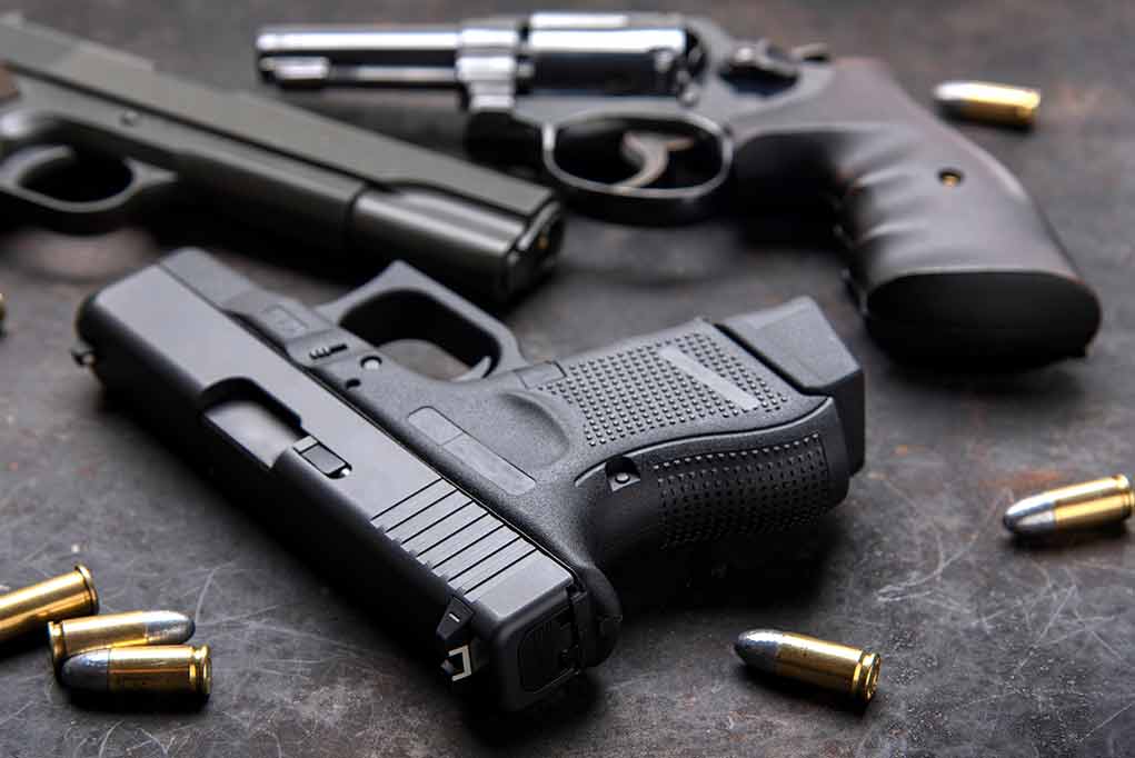 Handguns and bullets on a dark surface
