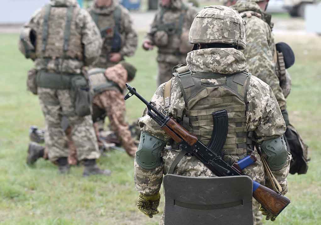 2057061182 featured image Soldiers in camouflage gear gathered on grass field.