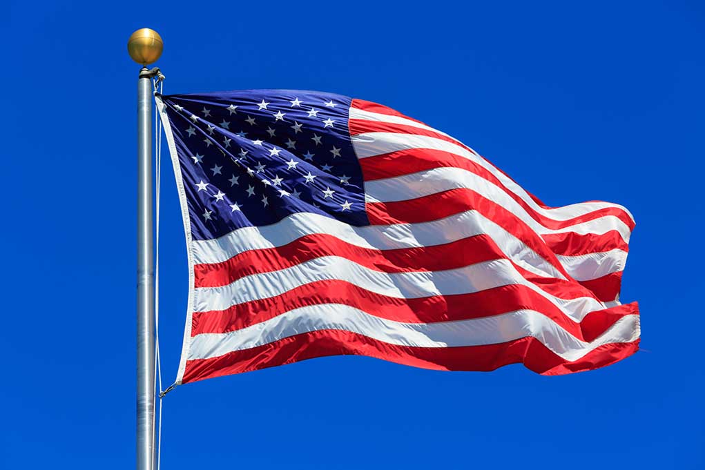 American flag waving against a clear blue sky.