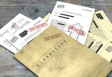 Classified documents with Top Secret stamps on wooden surface.