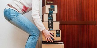 Person stacking Amazon boxes near door shoes nearby