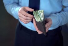 Person holding wallet filled with cash in hands