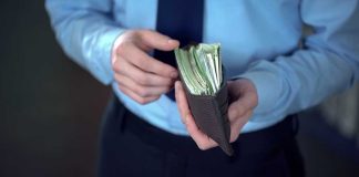 Person holding wallet filled with cash in hands