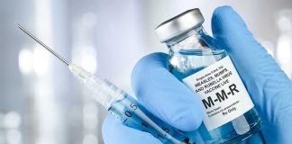 Syringe and MMR vaccine vial in gloved hand
