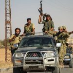Men in military gear on pickup truck