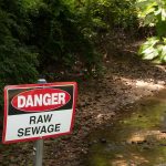 Danger sign near a stream with raw sewage.