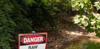Danger sign near a stream with raw sewage.