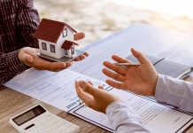 Hands exchanging miniature house over contracts