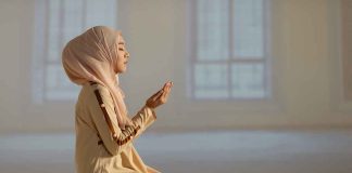 Woman praying indoors on a prayer mat.