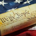 US Constitution on American flag background.