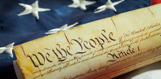 US Constitution on American flag background.