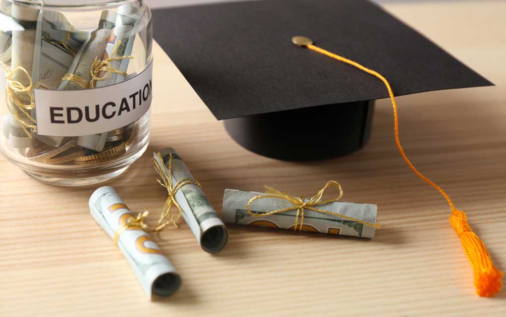 559683955 featured image Graduation cap with money rolls and jar labeled Education.