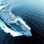 Military ship sailing swiftly on ocean waters