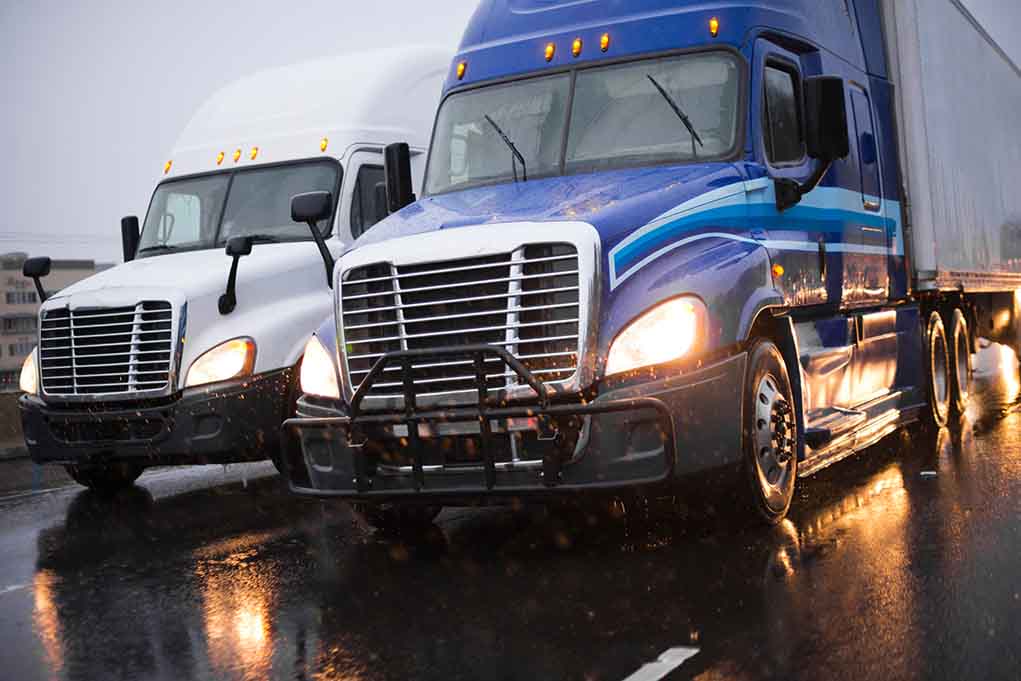 Two trucks driving on a wet road