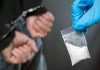 Person handcuffed police holding bag of white substance