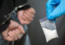 Person handcuffed police holding bag of white substance