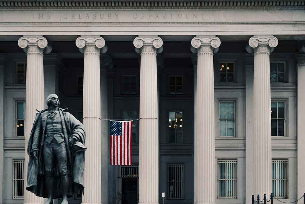 US Treasury Department building with statue and flag