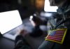 Soldier using laptop with US flag patch visible