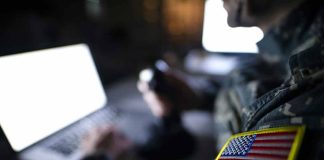 Soldier using laptop with US flag patch visible