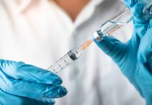 Gloved hands preparing syringe from vial