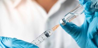 Gloved hands preparing syringe from vial