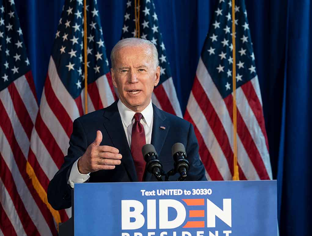 Man speaking at podium with American flags behind