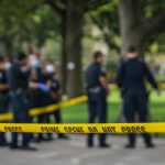 Police officers standing behind crime scene tape outside