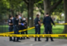 Police officers standing behind crime scene tape outside