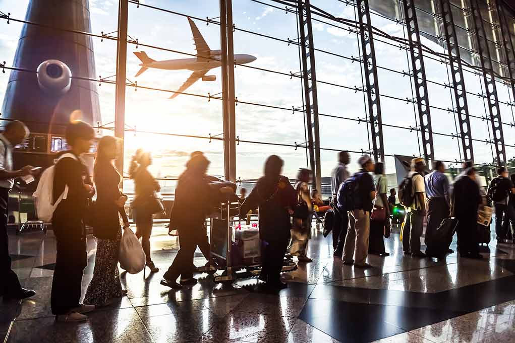 Passengers waiting at airport gate with airplane outside window