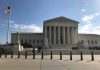 U S Supreme Court Building with flag and people outside