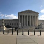U S Supreme Court Building with flag and people outside