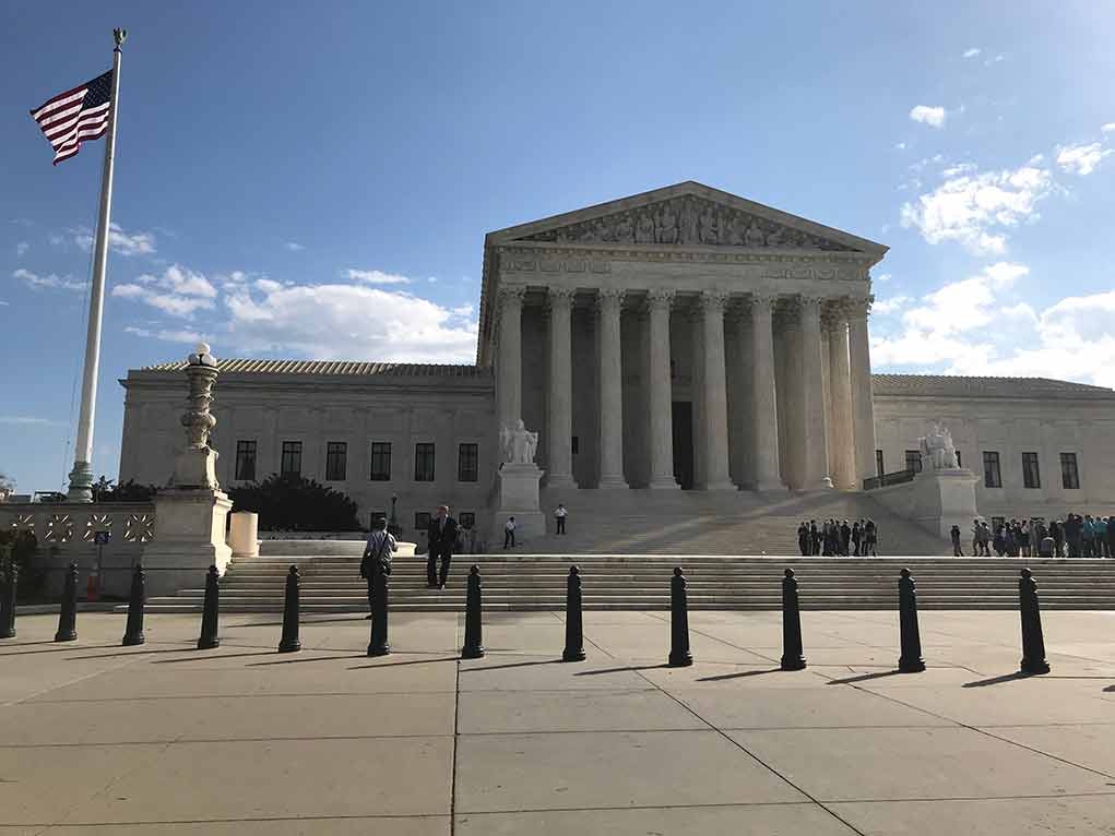 U S Supreme Court Building with flag and people outside
