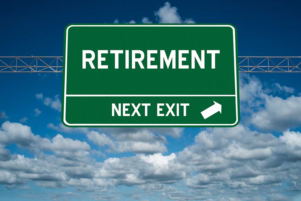 Green road sign reading retirement next exit sky background