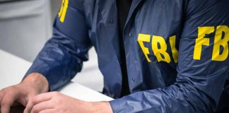 Person in FBI jacket typing on a laptop