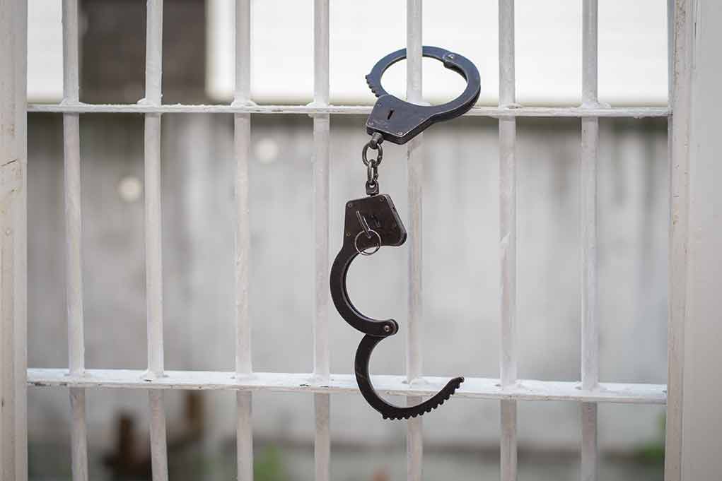 680970664 featured image Open handcuff hanging on white prison bars