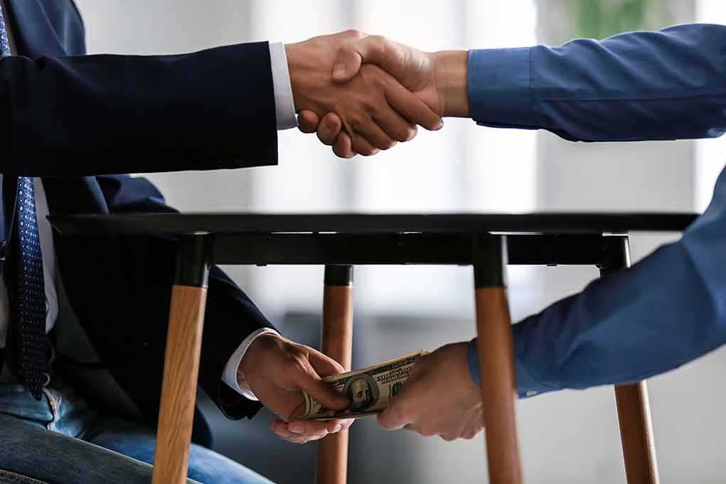 1225177960 featured image Handshake and exchange of money under the table