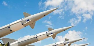 Multiple missiles pointed upward on launchers against blue sky